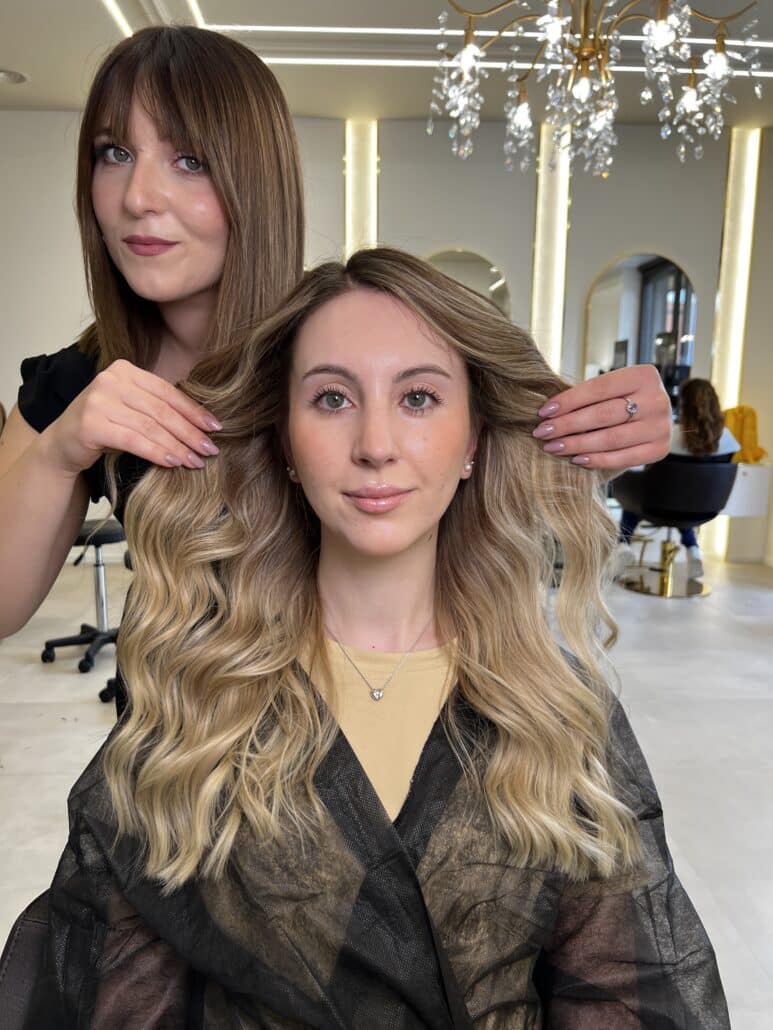 Hair stylist che valorizza una cliente con capelli biondo miele in onde naturali, realizzati nel BROSS Hair Lounge con il Metodo BROSS™.